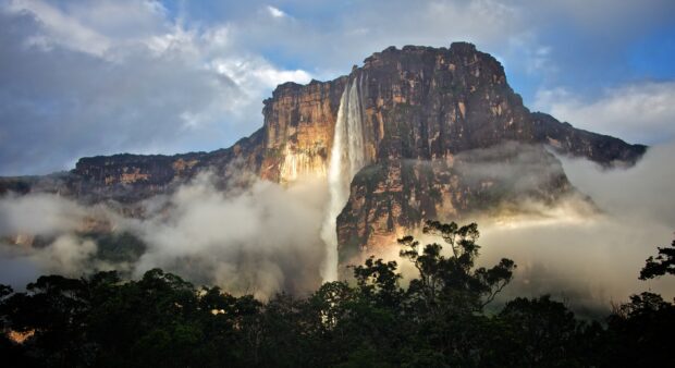 Angel Falls surrounded by mist and lush forest under a cloudy sky