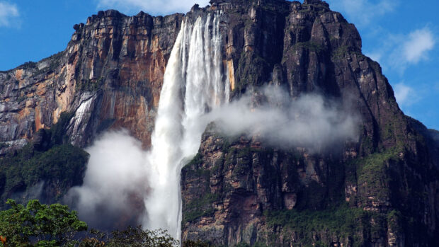 Angel Falls cascading down a steep cliff surrounded by clouds and lush greenery