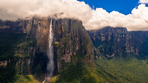 Angel Falls surrounded by lush greenery and towering cliffs under blue sky