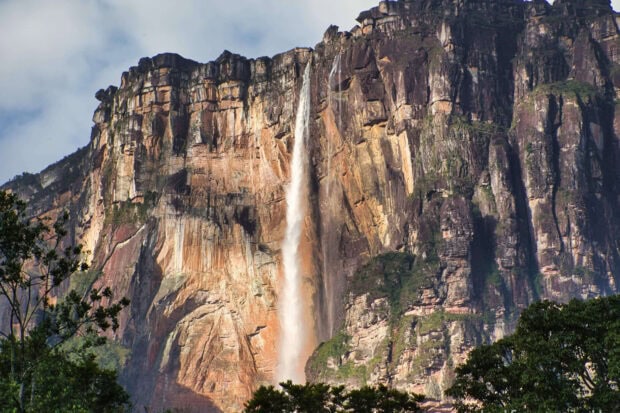 Angel Falls with high cliffs and lush greenery under a cloudy sky