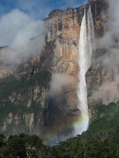 Angel Falls surrounded by mist and a rainbow in a lush forest landscape