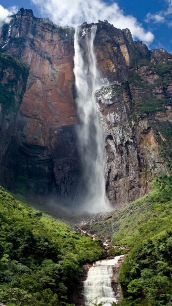 Angel Falls flowing down the cliffs surrounded by lush green forest and rocky terrain