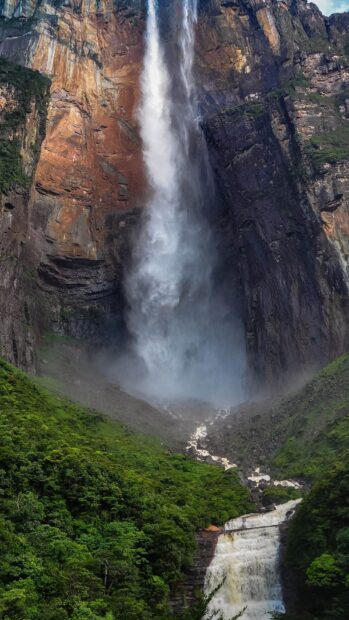 Angel Falls is a stunning natural waterfall surrounded by lush green forest and rocky cliffs