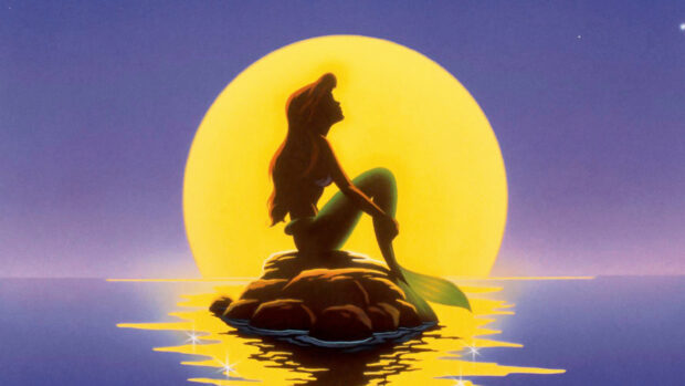 Ariel The Little Mermaid sitting on a rock with the moon glowing behind her silhouette