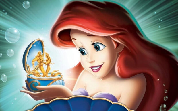 Ariel The Little Mermaid holding a golden mermaid figurine in an underwater scene