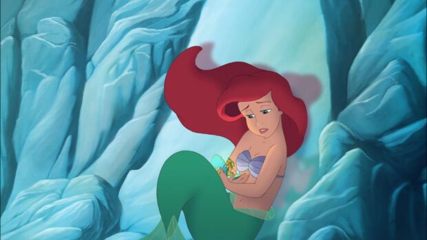 Ariel The Little Mermaid showing concern while holding a small glowing figure in a rocky underwater cave