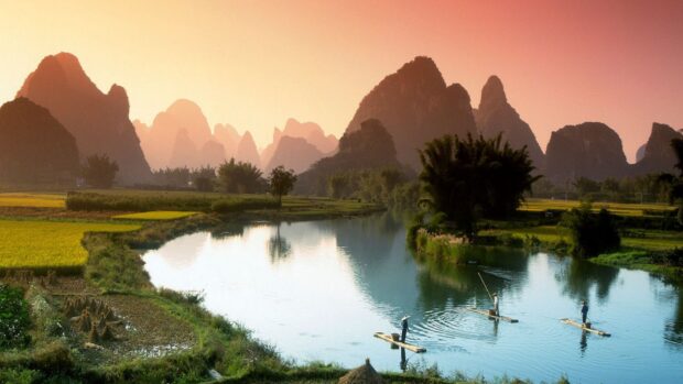 Asian landscape with karst mountains and bamboo rafts on the river at sunset