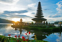 A serene view of Asia temple surrounded by lush greenery and water at sunrise