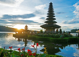 A serene view of Asia temple surrounded by lush greenery and water at sunrise