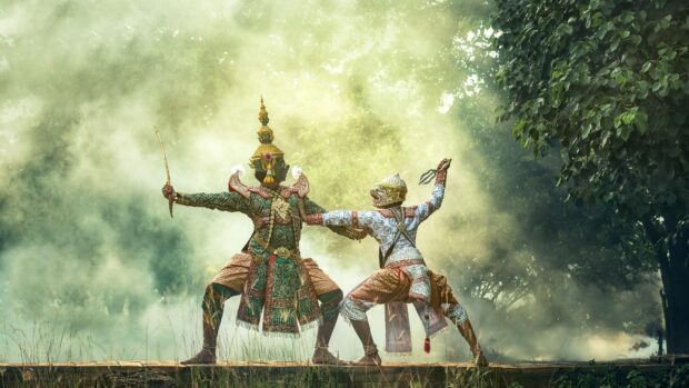 Two traditional Asian dancers perform a dramatic scene in detailed costumes in a misty outdoor setting