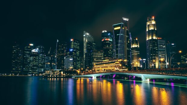 Modern cityscape in Asia at night with illuminated skyscrapers and bridge reflections