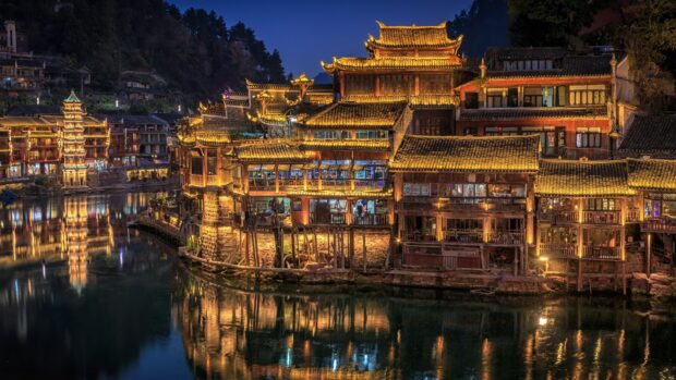 Traditional Asia architecture illuminated at night by river reflecting golden lights