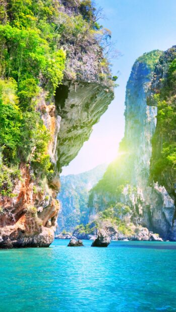 Clear blue sea with green cliffs and sunlight in an Asia coastal landscape