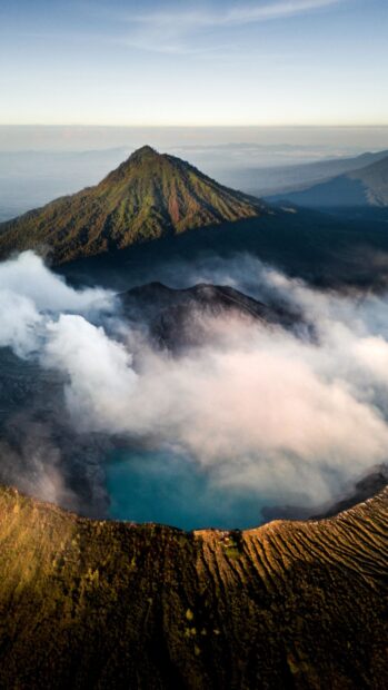 Volcanic crater lake surrounded by green mountains and mist in Asia