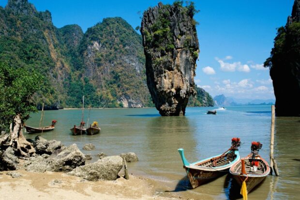 Traditional Asia boats docked near rocky shore with limestone formations in the sea