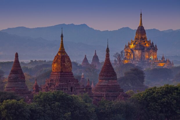 Ancient pagodas glowing at sunset in Asia mountain landscape