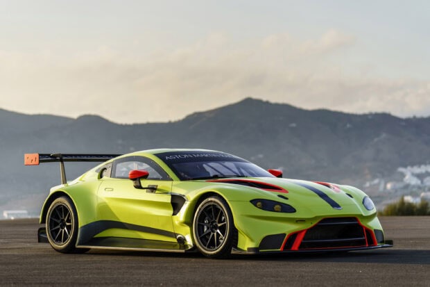 A bright green Aston Martin Vantage sports car parked on a race track with mountain background