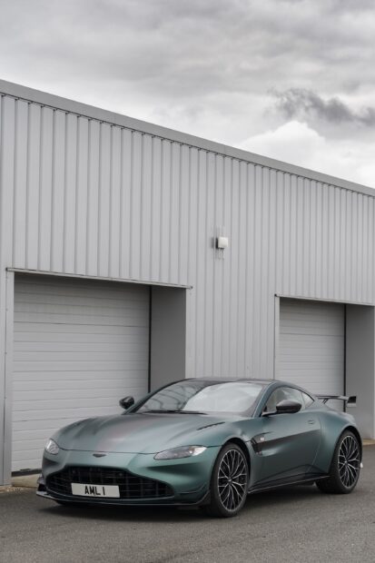 Green Aston Martin Vantage parked in front of a modern garage building