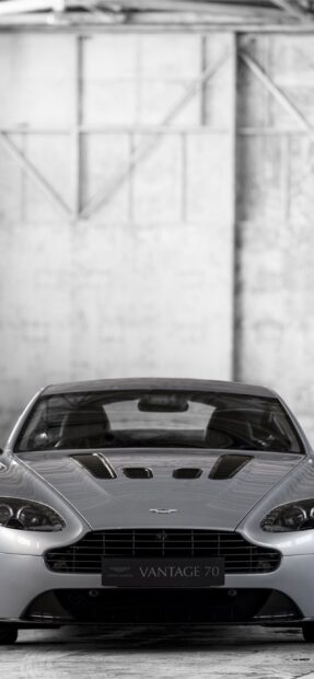 A silver Aston Martin Vantage sports car parked in an industrial setting