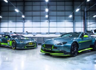 Two Aston Martin Vantage cars with green accents inside a modern garage