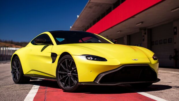 Yellow Aston Martin Vantage parked on a race track with clear blue sky
