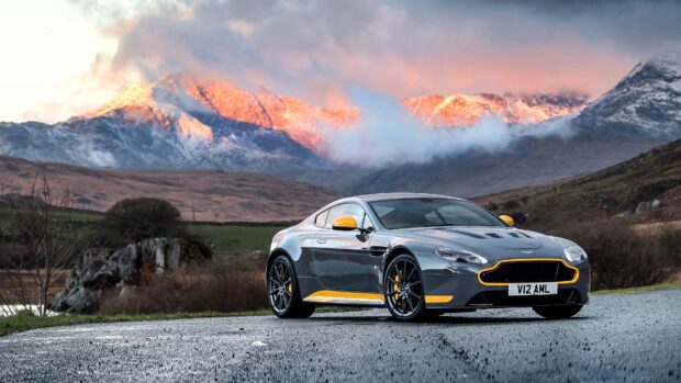 Aston Martin Vantage sports car with yellow accents parked on a mountain road