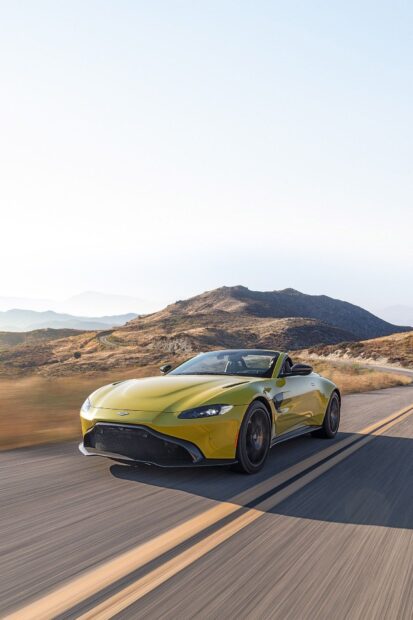 Yellow Aston Martin Vantage driving on a mountain road during daytime