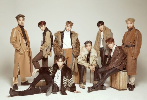 Ateez members posing in stylish brown and beige outfits in a studio setting