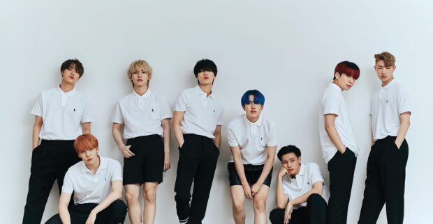 Ateez members posing in white shirts and black pants against a plain background
