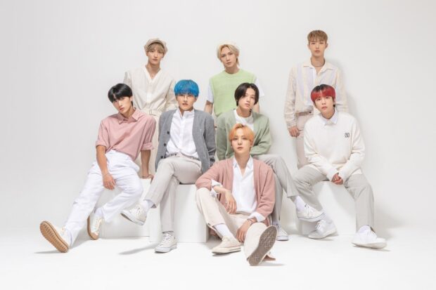 Ateez members posing in pastel outfits against a white background