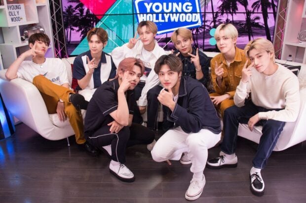 Ateez members posing together in a studio setting with Young Hollywood sign in the background