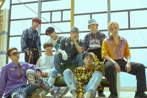 Ateez members posing together in casual stylish outfits in an industrial setting