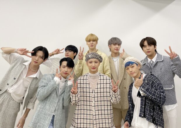 Ateez members posing together in coordinated outfits showing peace signs