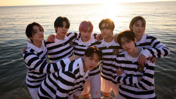Ateez members wearing striped shirts at the beach during sunset