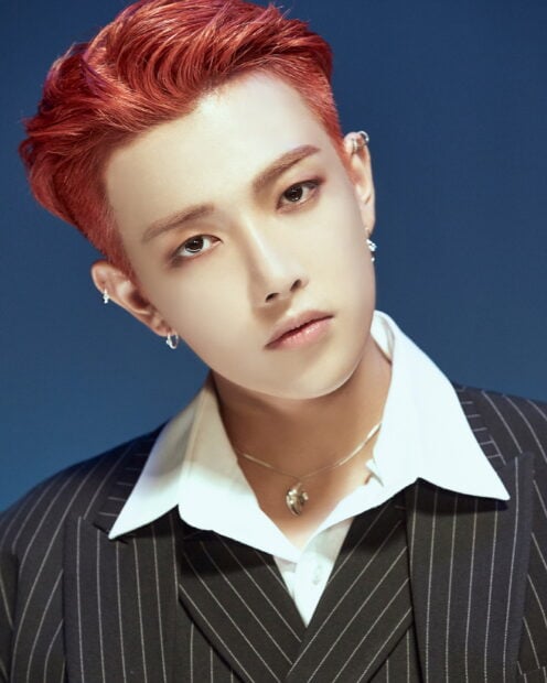 Close up of Ateez member with red hair and earrings looking at the camera