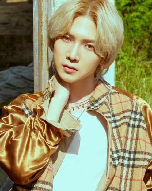 Ateez member posing outdoors in a golden plaid jacket with a thoughtful expression