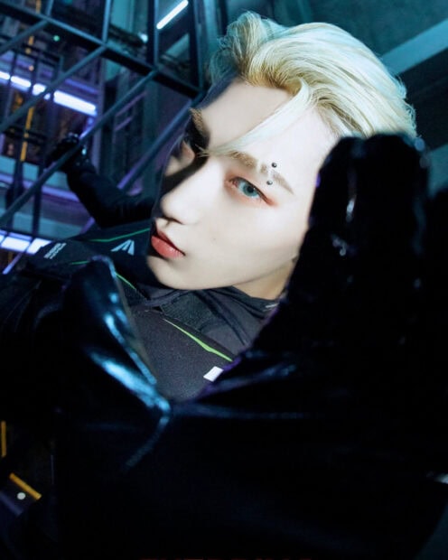 Close up of Ateez member with platinum blonde hair and blue eyes in a dark setting