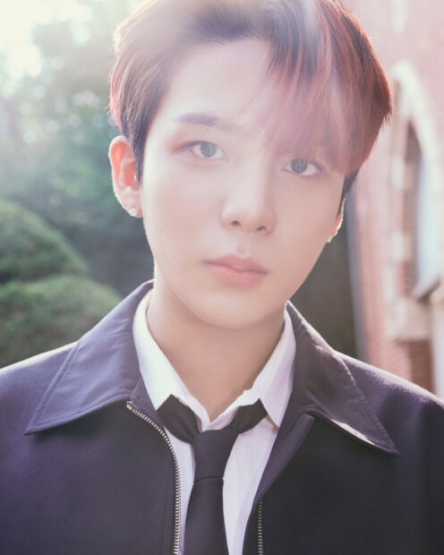 Close up of Ateez member with red hair in a formal outfit outdoors in soft natural light