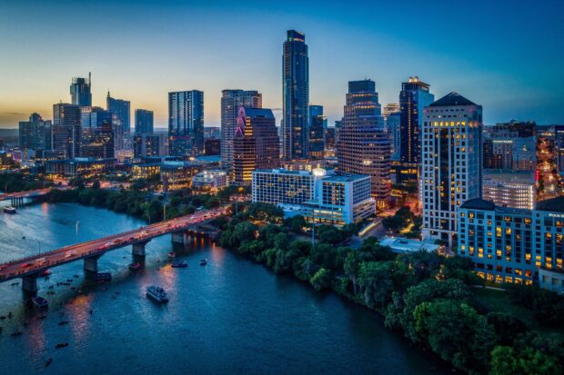 A scenic view of Austin skyline during twilight with river and illuminated buildings
