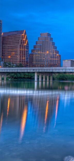 Tall Austin skyline reflecting in calm river water at dusk