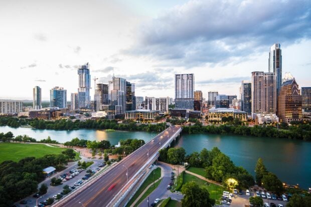 Austin cityscape with downtown skyline along the river at dusk featuring modern buildings and a bridge
