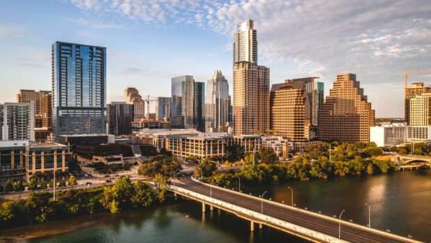 The Austin skyline with tall buildings and a river under a clear sky in golden hour