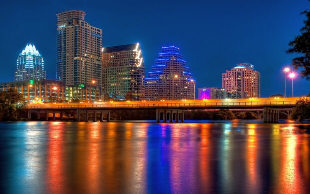 The Austin city skyline lit up at night with colorful reflections on the water