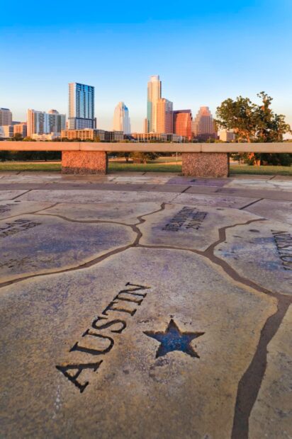 Map detail with Austin marked and city skyline in the background viewed at sunset