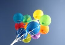 Colorful balloons floating in the clear sky with bright vibrant colors and strings attached