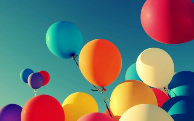 Colorful balloons floating in the clear sky with vibrant shades of blue orange red and yellow