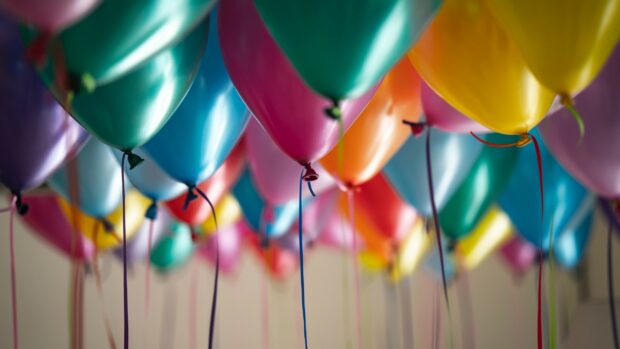 Colorful balloons floating indoors with bright ribbons hanging down