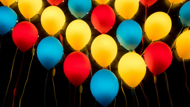 Colorful balloons illuminated against a dark background creating a vibrant display