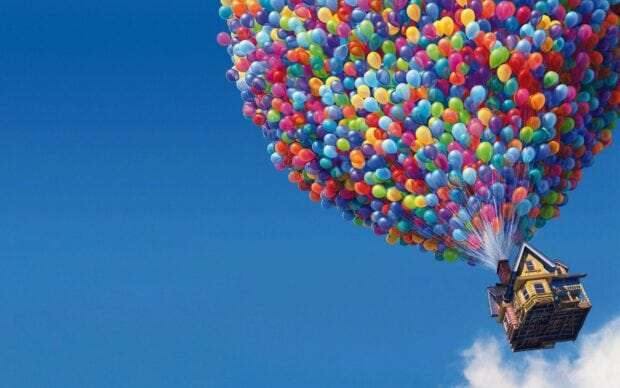 A large cluster of colorful balloons lifting a house into the clear blue sky