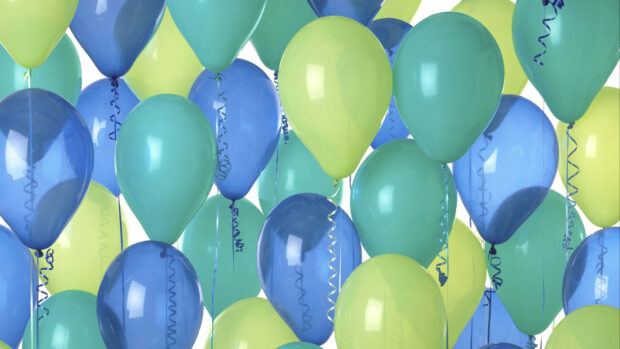 Blue and green balloons floating together in a group